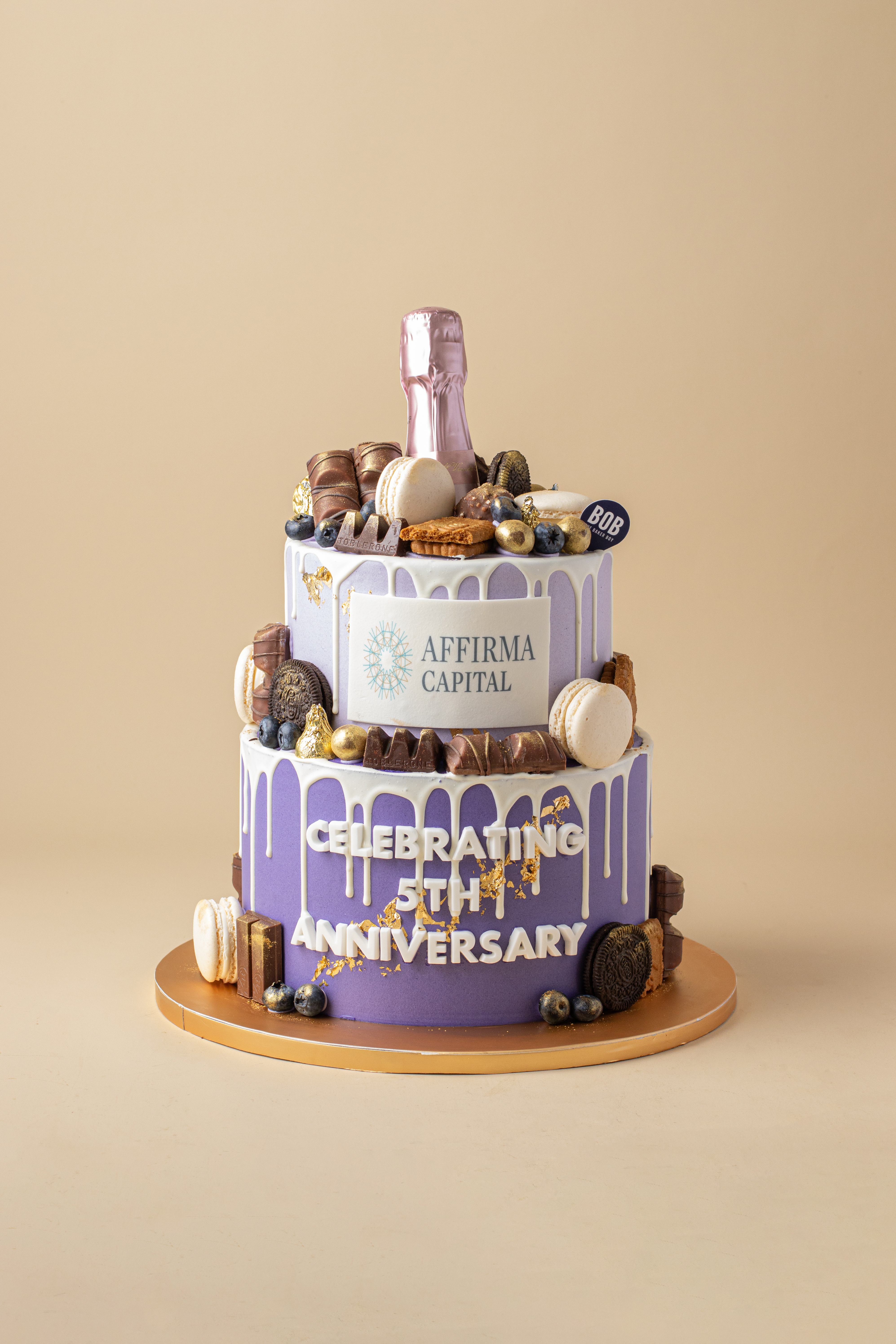 Affirma Capital 5th Anniversary tiered corporate cake with edible logo print and champagne bottle topper